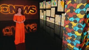 Imagem da apresentadora Leilane Neubarth no estúdio da GloboNews, ao lado de telões de led com o logo na emissora em um painel ao fundo