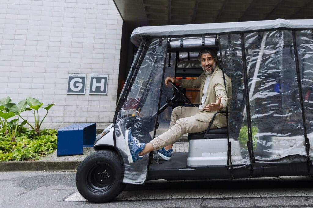 Imagem com Marcos Mion em um dos carrinhos de transporte de pessoas dos Estúdios Globo