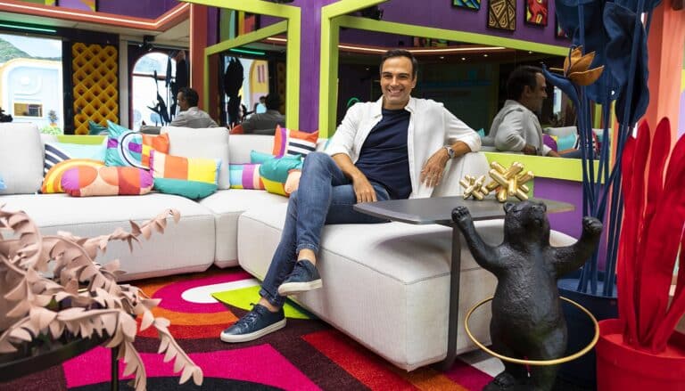 Imagem com foto de Tadeu Schmidt sentado no sofá da sala do BBB22
