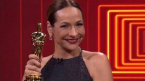 A foto mostra a apresentadora Maria Beltrão de traje de gala com a estatueta do Oscar