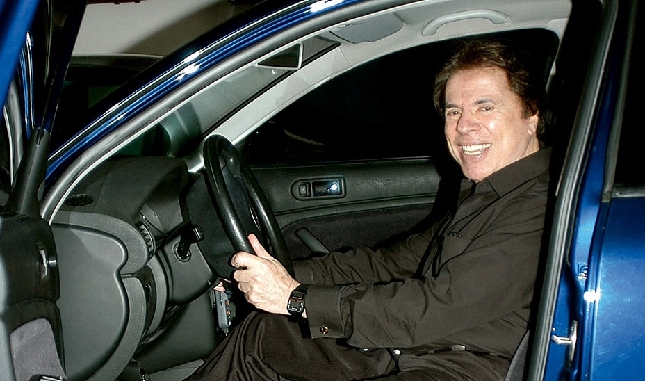 Foto do apresentador Silvio Santos dirigindo o seu carro
