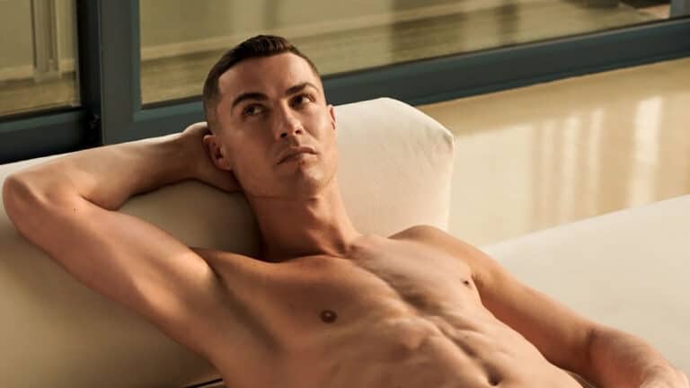 Imagem com foto do jogador Cristiano Ronaldo. Ele está deitado em um sofá sem camisa