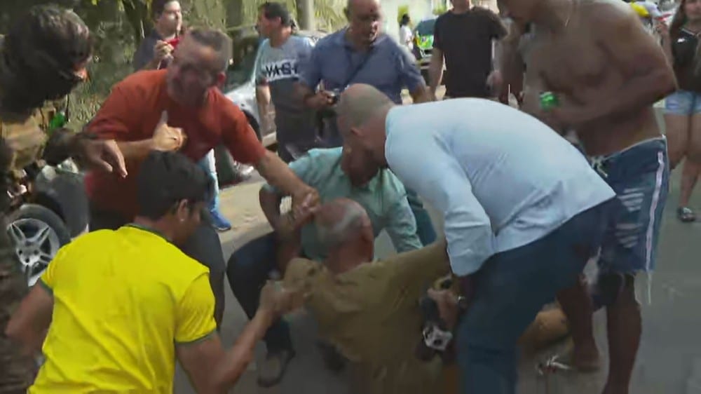Imagem com foto do cinegrafista Rogério de Paula sendo socorrido após ataque de apoiadores de Roberto Jefferson