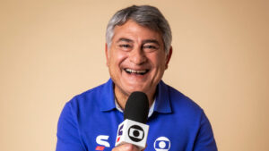 Imagem com foto do narrador Cléber Machado segurando o microfone da Globo