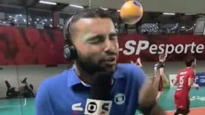 Imagem com foto do momento em que o repórter Plácido Berci, da Globo, leva bolada durante transmissão de partida de vôlei