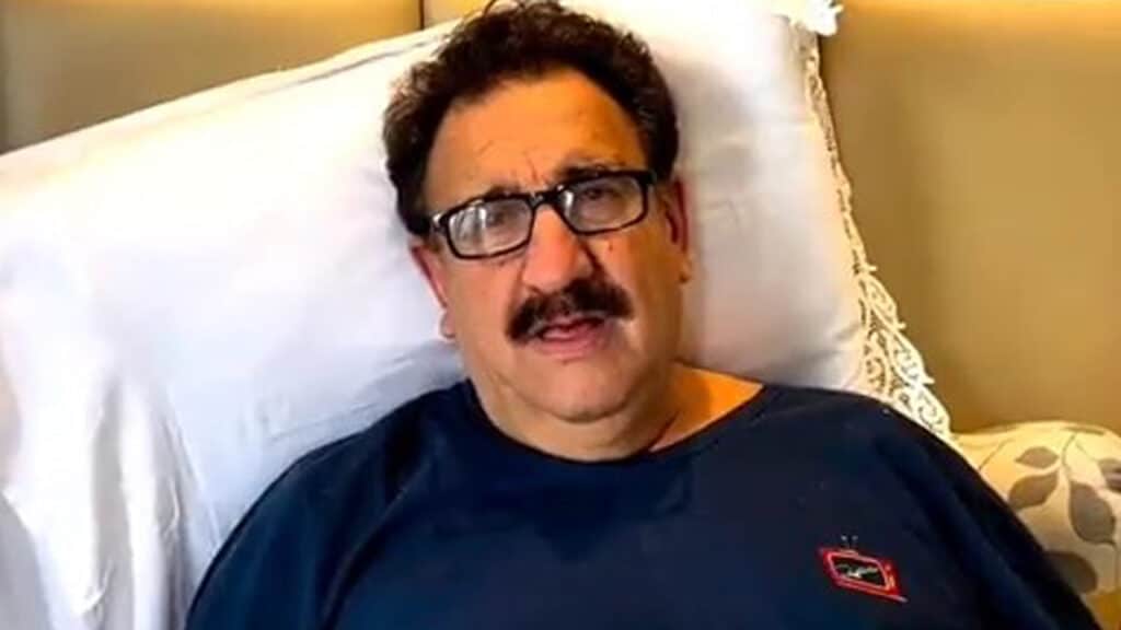 Imagem com foto do apresentador Ratinho deitado em uma cama se recuperando de uma cirurgia