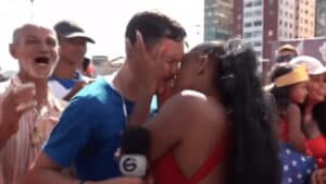 Imagem com foto do momento em que o repórter Rodrigo de Luna é surpreendido com beijo de humrorista