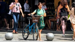 Imagem com foto da atriz Alexandra Marzo empurrando bicicleta pelas ruas do Leblon