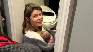 Imagem com foto da âncora Kasie Hunt, da CNN, no chão do banheiro de casa com a bebê no colo