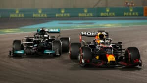 Imagem com foto do momento em que Max Verstappen ultrapassa Lewis Hamilton no GP de Abu Dhabi em 2021