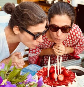 Imagem com foto de Renata Vasconcellos e Lanza Mazza soprando velinhas do bolo de aniversário
