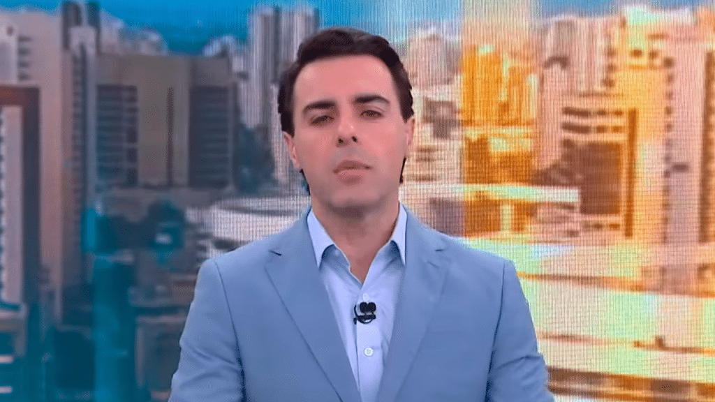 Rafael Colombo durante apresentação do telejornal Novo Dia na CNN Brasil. Ele está de terno, sem gravata, na bancada do telejornal