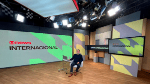 O jornalista Marcelo Lins sentado em uma poltrona no novo cenário do GloboNews Internacional