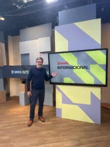 O jornalista Marcelo Lins em frente a um dos telões do novo cenário do GloboNews Internacional