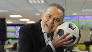 Luís Roberto, narrador da Globo no Campeonato Brasileiro, abraçado em uma bola de futebol