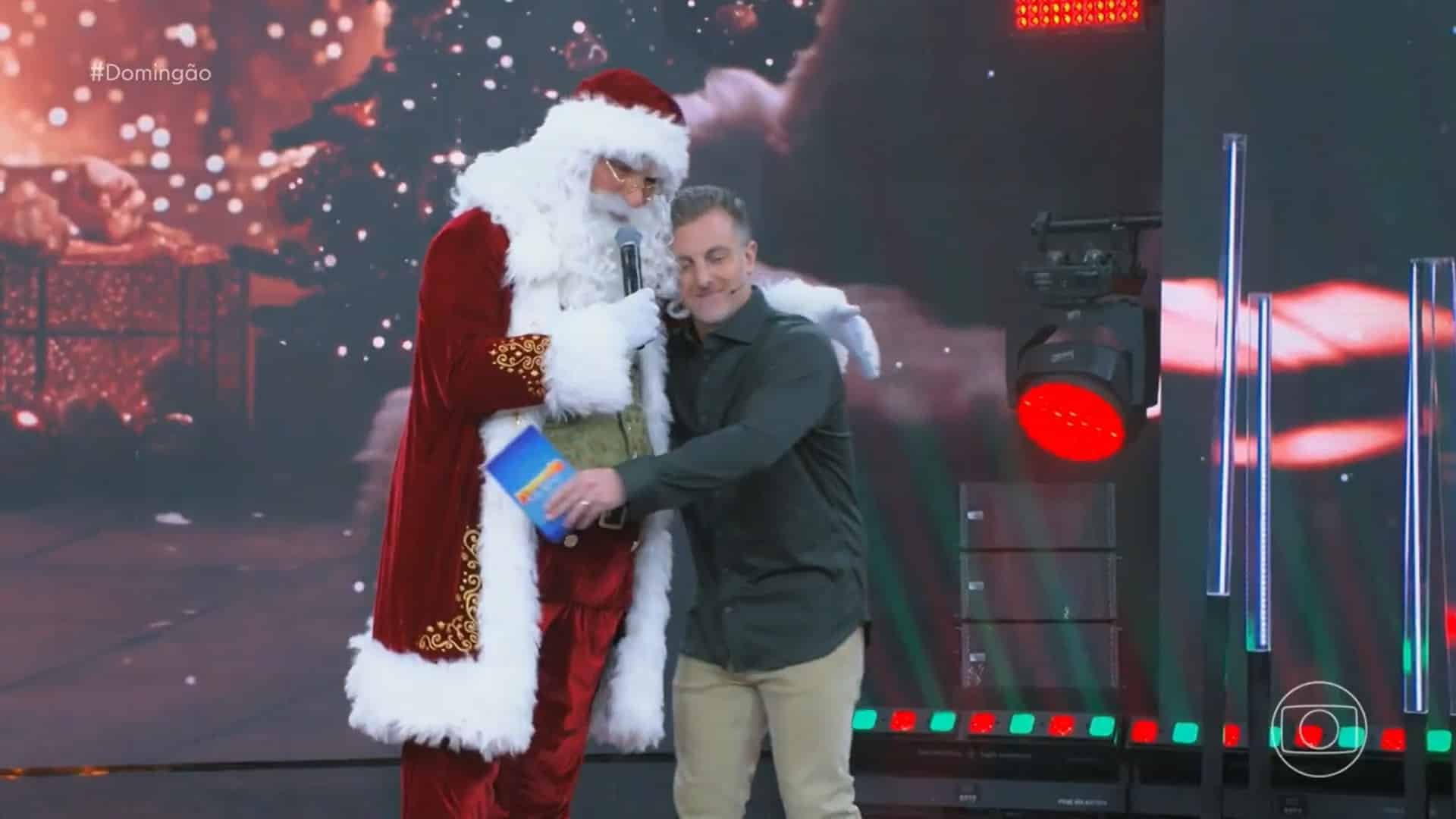 Foto do apresentador Luciano Huck abraçando o Papai Noel no especial do Domingão
