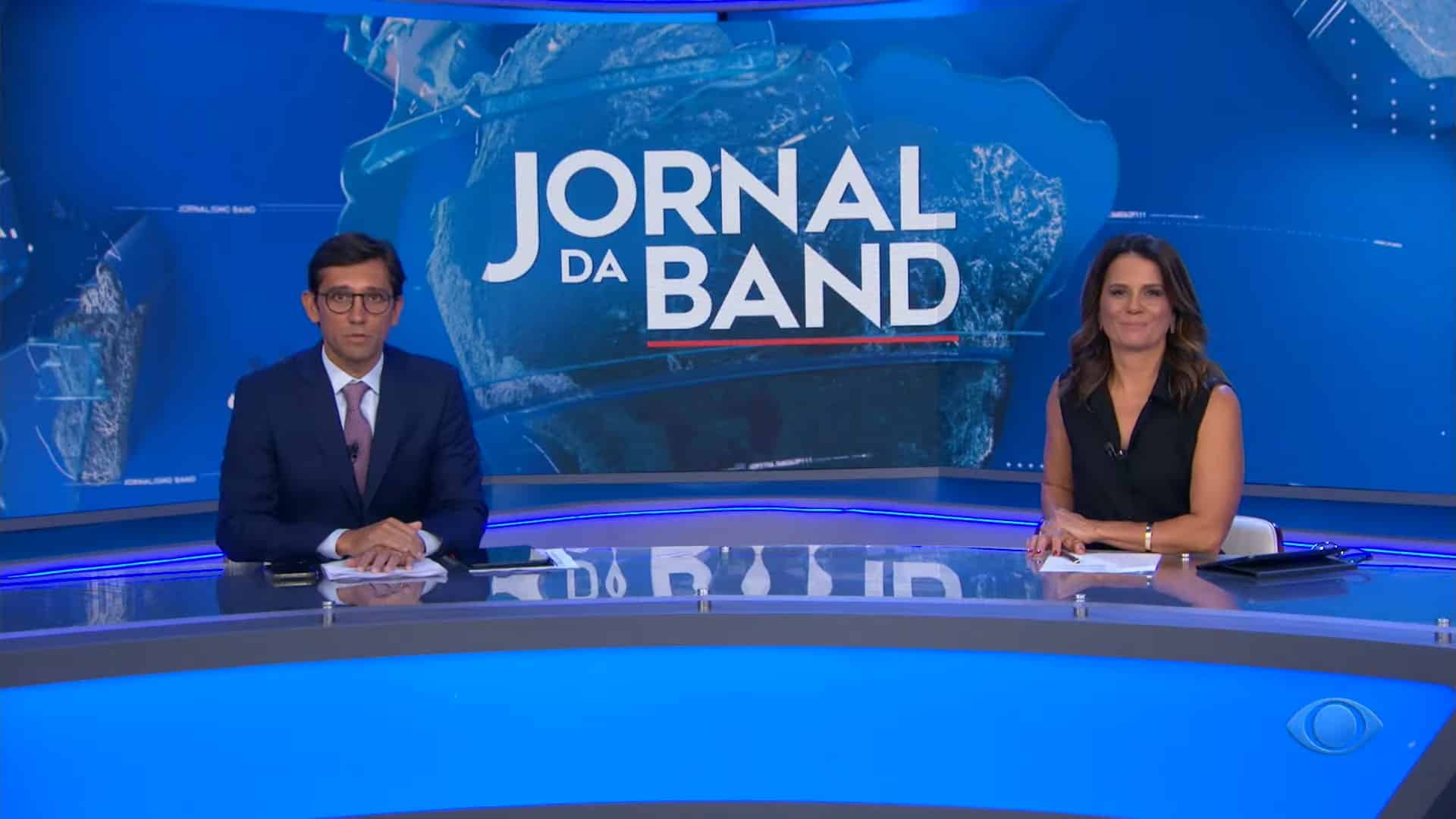 Foto de Rodolfo Schneider e Adriana Araújo na bancada do Jornal da Band