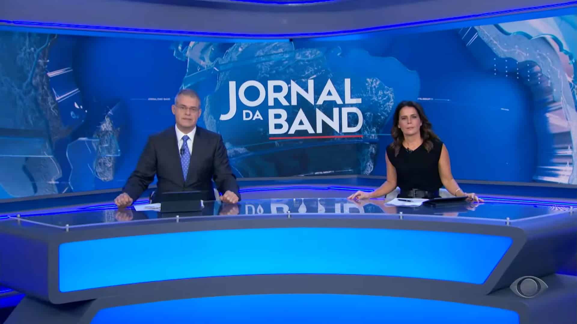 Foto de Eduardo Oinegue e Adriana Araújo na bancada do Jornal da Band