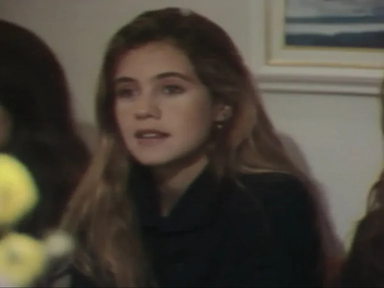 Adriana Esteves, ainda jovem, aparece em cena de Vale Tudo (1988). Com cabelos longos e soltos, a atriz usa maquiagem discreta e veste uma blusa escura. Ela surge em um ambiente interno, com expressão atenta e delicada, evidenciando a fase inicial de sua carreira na televisão.