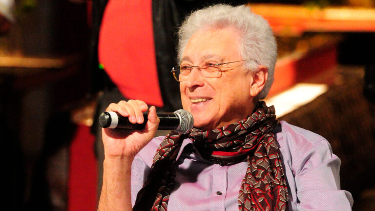 Aguinaldo Silva, autor da novela da Globo Três Graças, segurando microfone durante evento