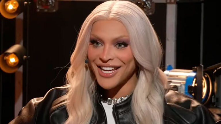 Pabllo Vittar com microfone de lapela durante entrevista em estúdio com iluminação de bastidores ao fundo