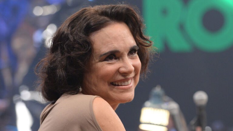 Regina Duarte sorrindo durante participação no Altas Horas com plateia e cenário ao fundo