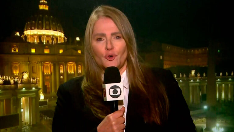 Ilze Scamparini segurando microfone da TV Globo em frente à Basílica de São Pedro durante reportagem no Vaticano