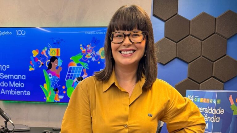 Mariana Bridi sorrindo em frente a tela da 10ª Semana do Meio Ambiente na Globo