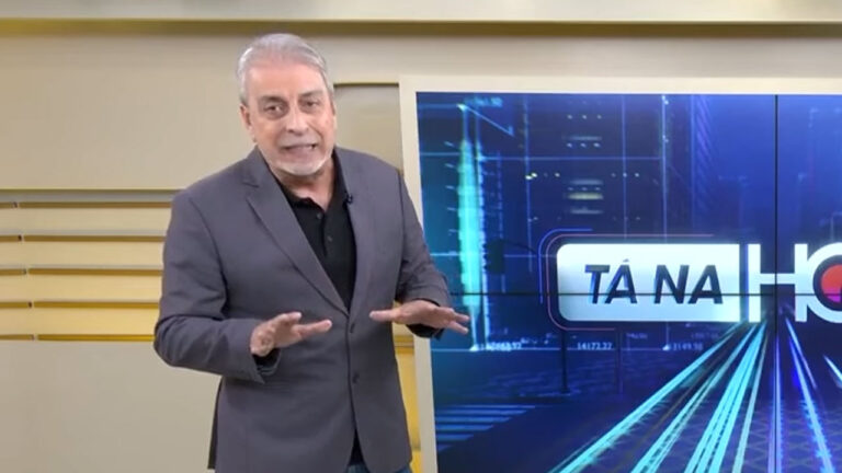 Clóvis Monteiro gesticula em frente ao telão com o logo do Tá na Hora Rio do SBT no estúdio