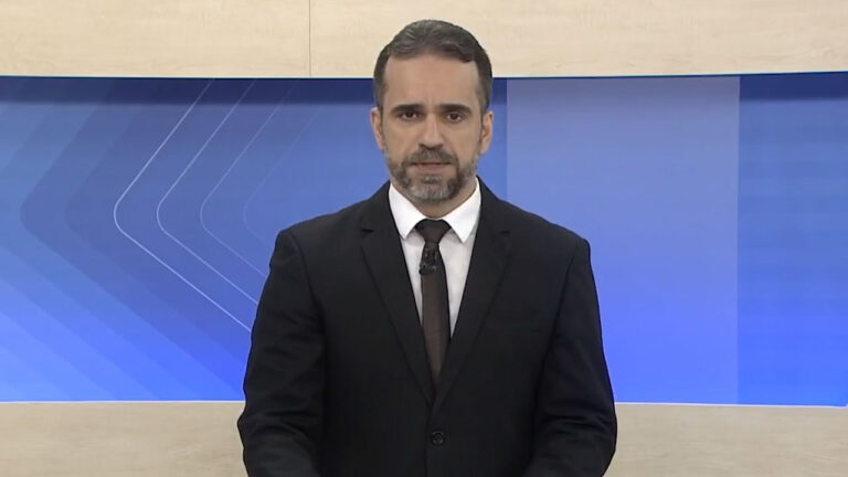 Filipe Toledo apresenta o telejornal AL2 da TV Gazeta de Alagoas, afiliada da Globo, em estúdio com fundo azul