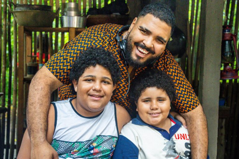O ChatGPT disse: Paulo Vieira e atores mirins de Pablo e Luisão posam sorrindo em set da série do Globoplay