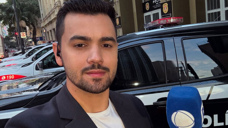 Yuri Macri com microfone da Record em frente a viatura da polícia civil durante reportagem na rua