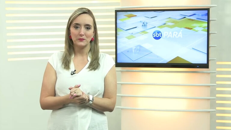 Bianca Teixeira em pé no estúdio do SBT Pará com o logo do telejornal exibido em tela ao fundo
