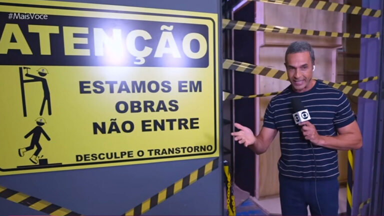 Fabrício Battaglini com microfone da Globo em frente à porta interditada por obras no estúdio do Mais Você