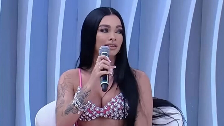 Gisa Custolli com microfone na mão falando durante participação no programa Superpop