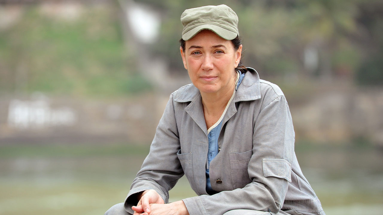 Lilia Cabral caracterizada como Griselda, o Pereirão, usando macacão cinza e boné verde na novela Fina Estampa