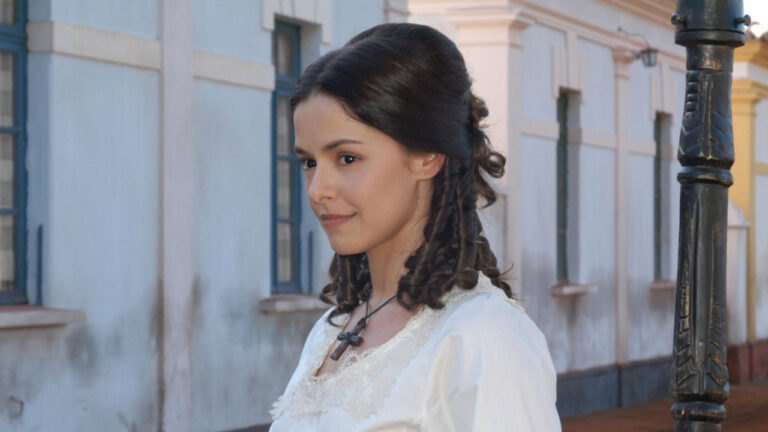 Bianca Rinaldi caracterizada como Isaura com vestido branco e cabelo preso em cena da novela A Escrava Isaura