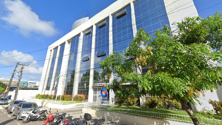 Fachada do prédio da TV Guararapes afiliada da Record em Pernambuco com logo Opinião Sistema de Comunicação na entrada