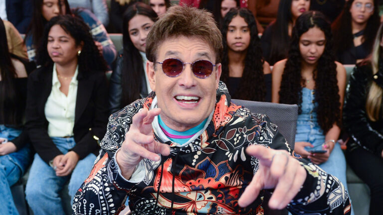 Sérgio Mallandro de óculos escuros e blusa estampada no quadro Dez ou Mil do Programa do Ratinho com plateia ao fundo