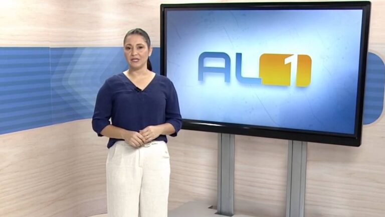Chrystiane Gonçalves apresenta o AL1 em frente ao telão com logotipo do telejornal na TV Gazeta de Alagoas