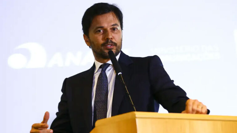 Fábio Faria fala ao microfone em púlpito de madeira durante evento oficial do Ministério das Comunicações