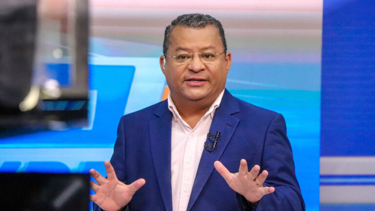 Nilvan Ferreira de terno azul apresenta o programa Tribuna Livre da TV Arapuan em estúdio de telejornal