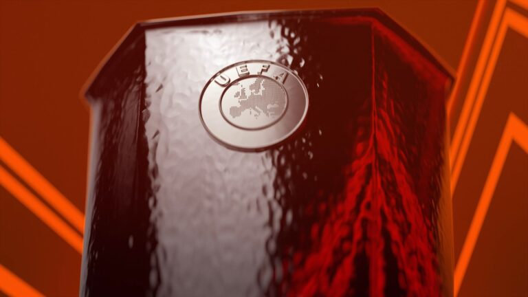 Detalhe do troféu da Europa League com o logotipo da UEFA em destaque sobre fundo vermelho