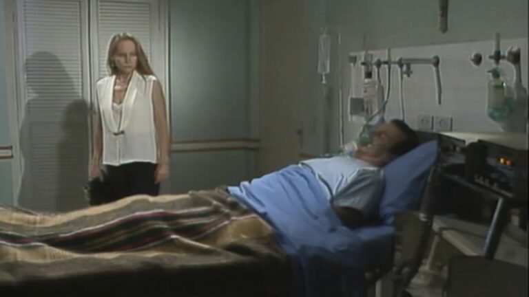 Cena da novela A Viagem mostra um homem deitado em uma cama de hospital, usando máscara de oxigênio, enquanto uma mulher o observa em pé ao lado, em um ambiente de iluminação suave e atmosfera dramática