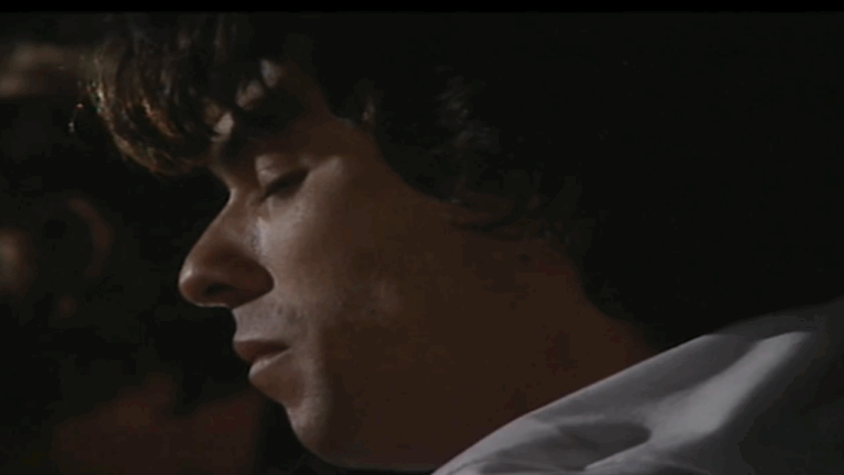 Cena da novela A Viagem mostra um homem de olhos fechados em close, com expressão séria e iluminação suave e escura