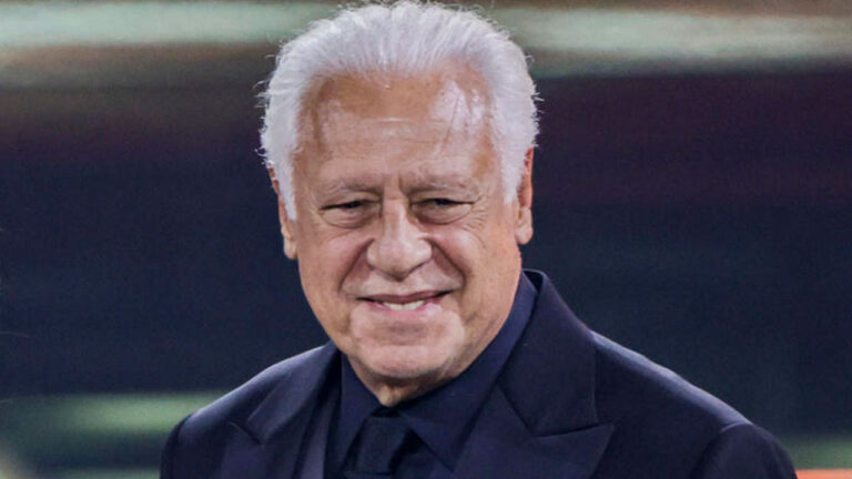 O ator Antonio Fagundes, com cabelo todo branco e vestindo terno e camisa escuros, sorri com o olhar para baixo durante um evento