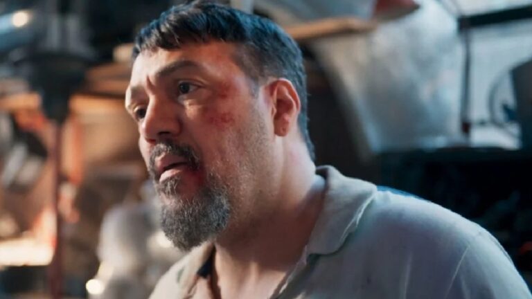 Belo com expressão abatida e marcas no rosto em ambiente industrial com iluminação suave