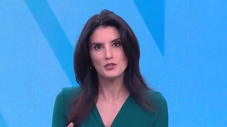 Carol Nogueira apresenta telejornal da CNN Brasil vestindo roupa verde diante de fundo azul no estúdio