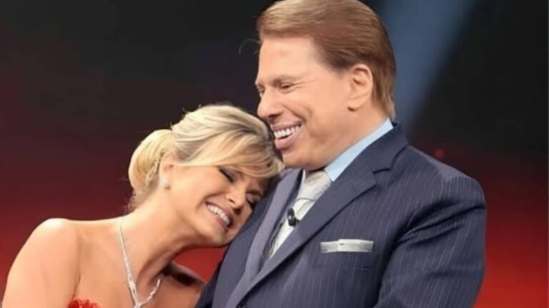 Eliana e Silvio Santos sorrindo juntos em um estúdio de TV, demonstrando carinho e amizade — ela encostada no ombro dele, ambos bem-humorados e elegantes