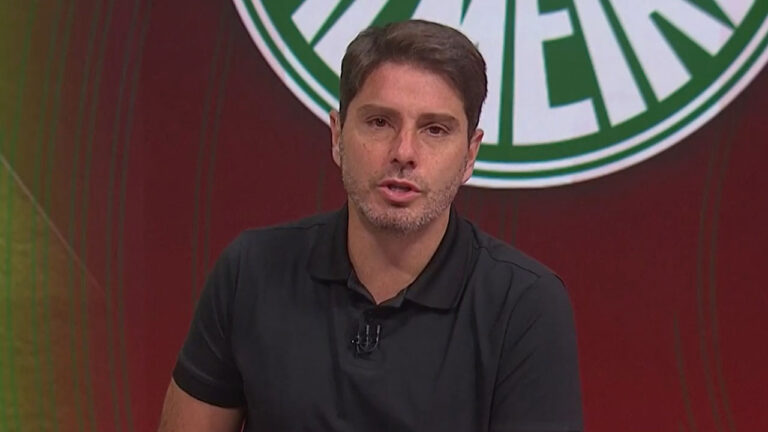 Felipe Diniz, com camisa polo preta, fala no programa Troca de Passes, do SporTV, em estúdio com cenário vermelho e verde